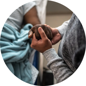 A zoomed in hospital setting showing a patient's hand being held by a loved one