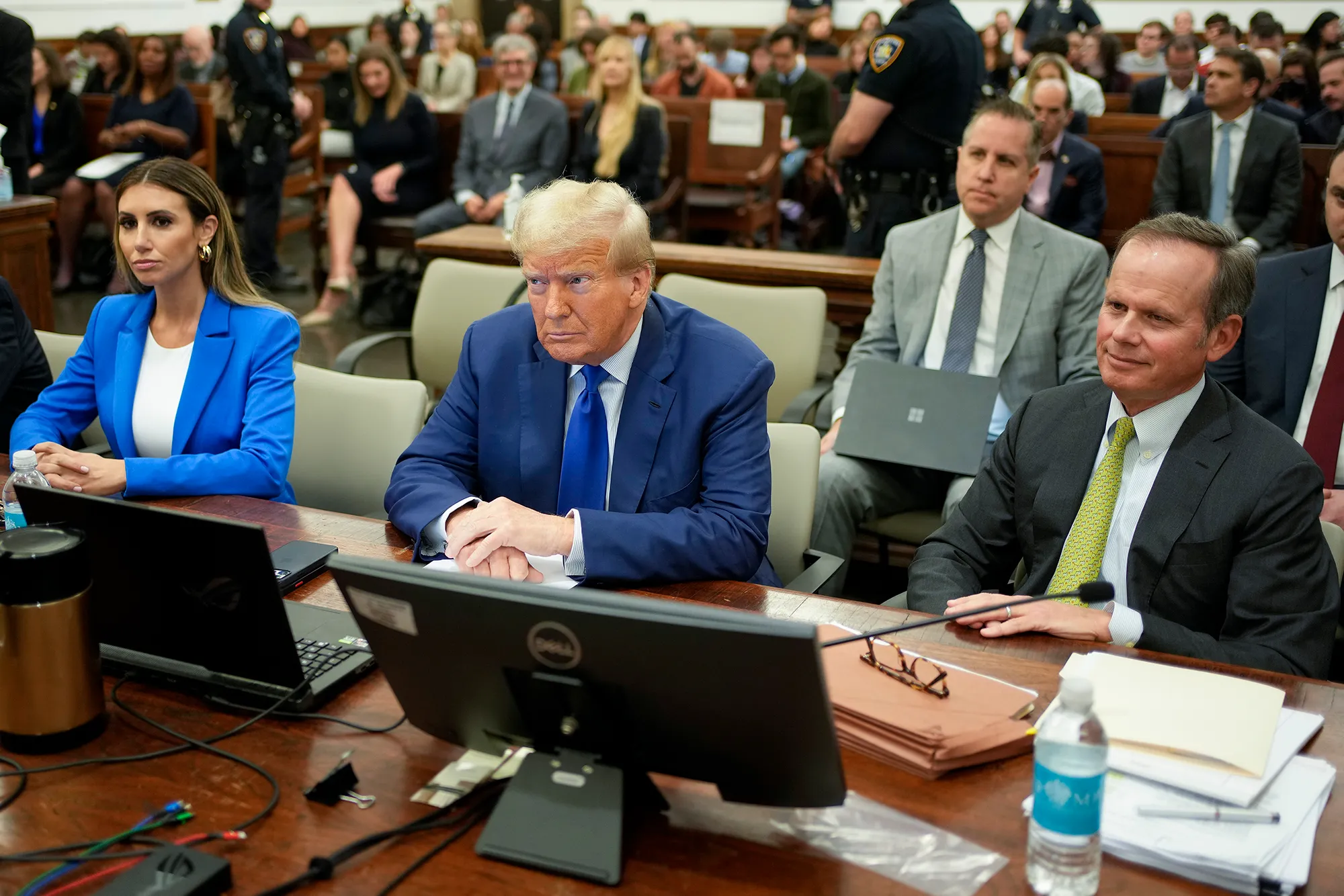 Former President Donald Trump sitting with lawyers Alina Habba and Christopher Kise in court.