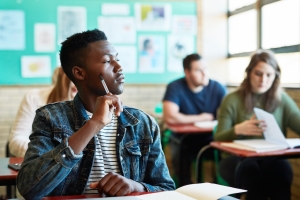 Student in a classroom looking pensively out of the window. Other student images slightly blurred.