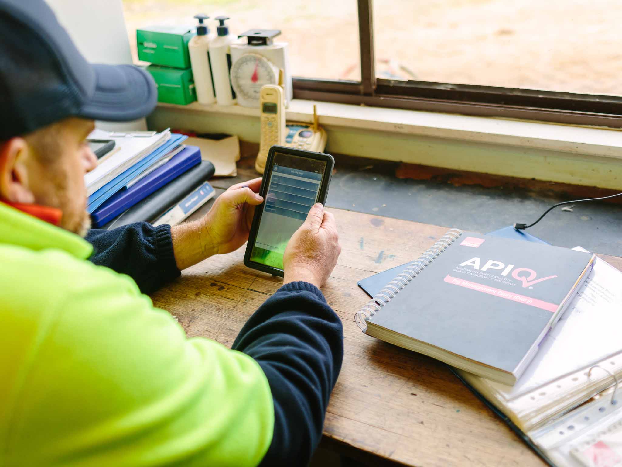 Man holding tablet with APIQ booklet to his right