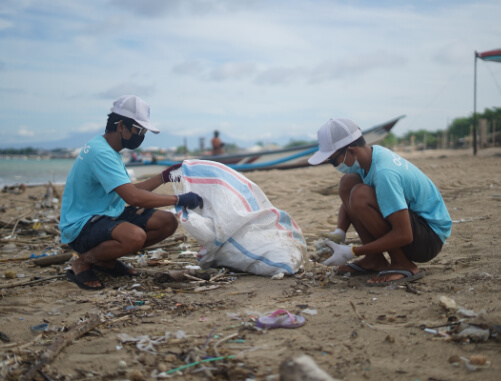 duas pessoas realizando serviço voluntário em uma praia de São Paulo