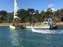 An old abandoned vessel getting lifted with floats and towed away for disposal in a landfill.