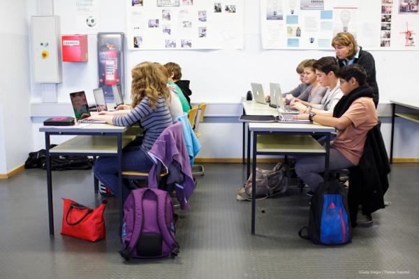 A teacher monitoring her students using laptops in a classroom.