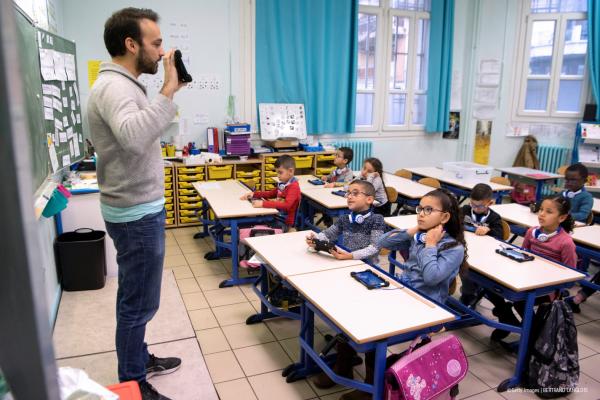 A teacher showing his students how to use a tablet in a classroom.