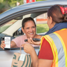 A team member hands a guest a Starbucks bag at drive up