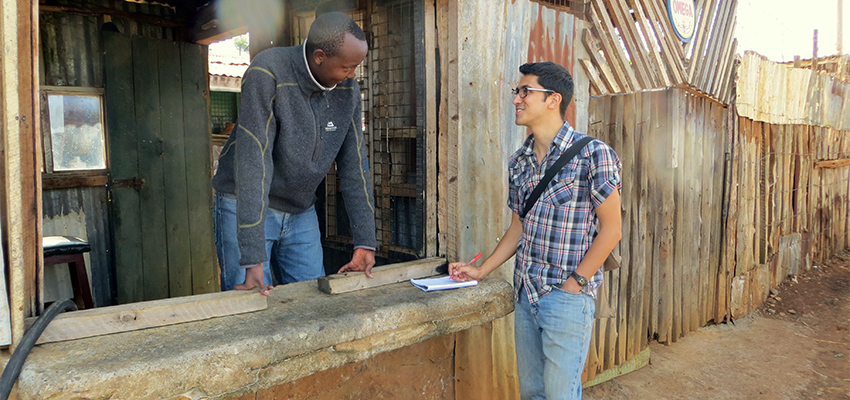 Man leaning out of a ground-floor window talking to a younger man standing outside with a notebook.