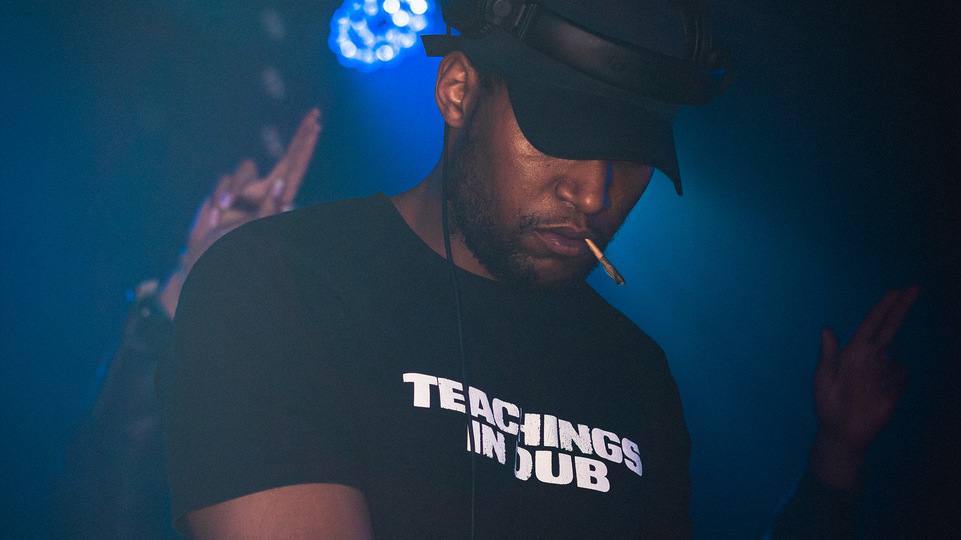 Photo of Joker wearing a black hat and t-shirt reading ‘Teachings In Dub’