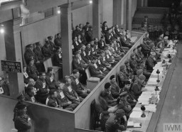 Wearing numbers, the defendants in the Bergen-Belsen Trial sit in the courtroom in Lüneburg, Germany. IWM (HU 59545)