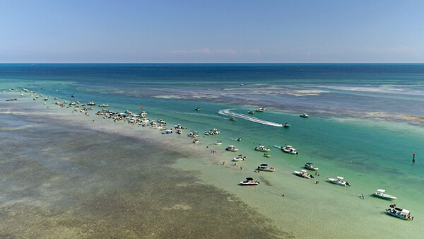 An aerial view of several boats pulled up to a sandbar