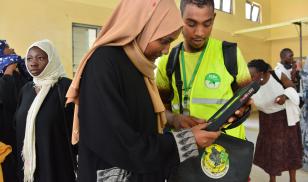 A voter educator with the Independent Electoral and Boundaries Commission in Mombasa, Kenya assists a voter to confirm their voter status and voting station during a Civic Engagement Forum at Majengo Village Hall