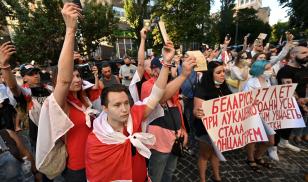 Members of the Belarusian diaspora in Ukraine hold their passports at a rally outside the Belarusian embassy in Kyiv in August 2021 to mark the first anniversary of the fraudulent 2020 presidential election in Belarus. 