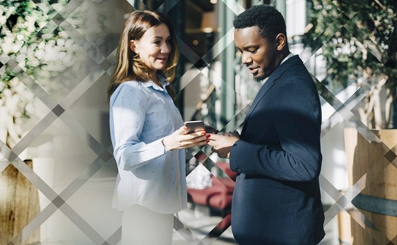 A man and a woman outdoors looking at a phone