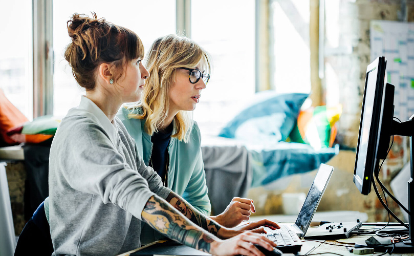 Two women in an office setting looking at the computer