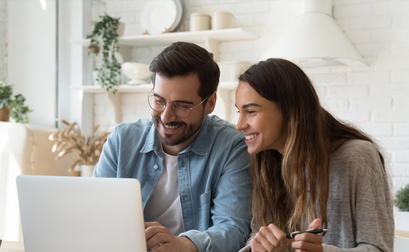 Un homme et une femme souriant à un ordinateur