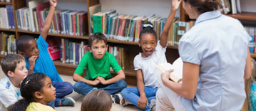 Teacher reading to and taking questions from a group of young students