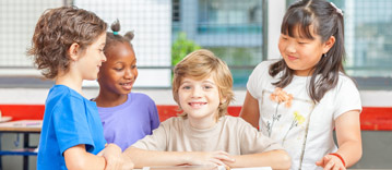 Four children at a desk in classroom