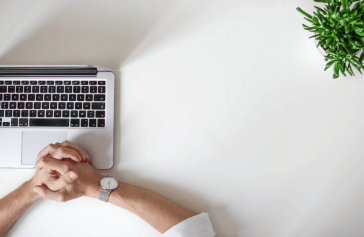 folded hands next to laptop ready to work