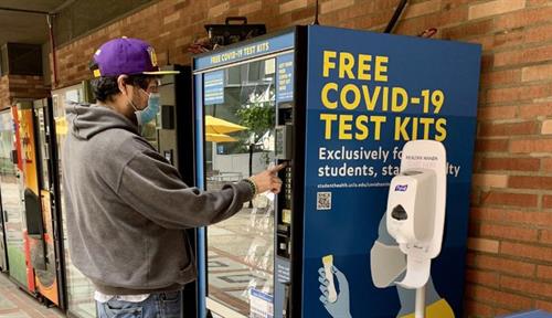 A UCLA staff member collects a free Covid-19 self-test from an on-campus vending machine.