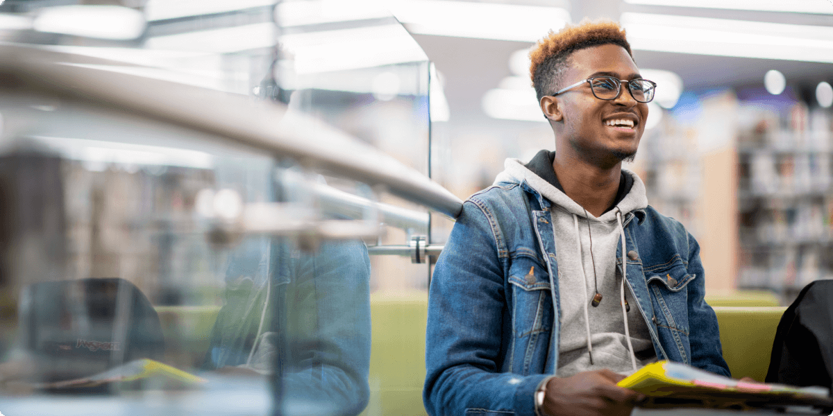 A young man enthusiastically smiles in a library.