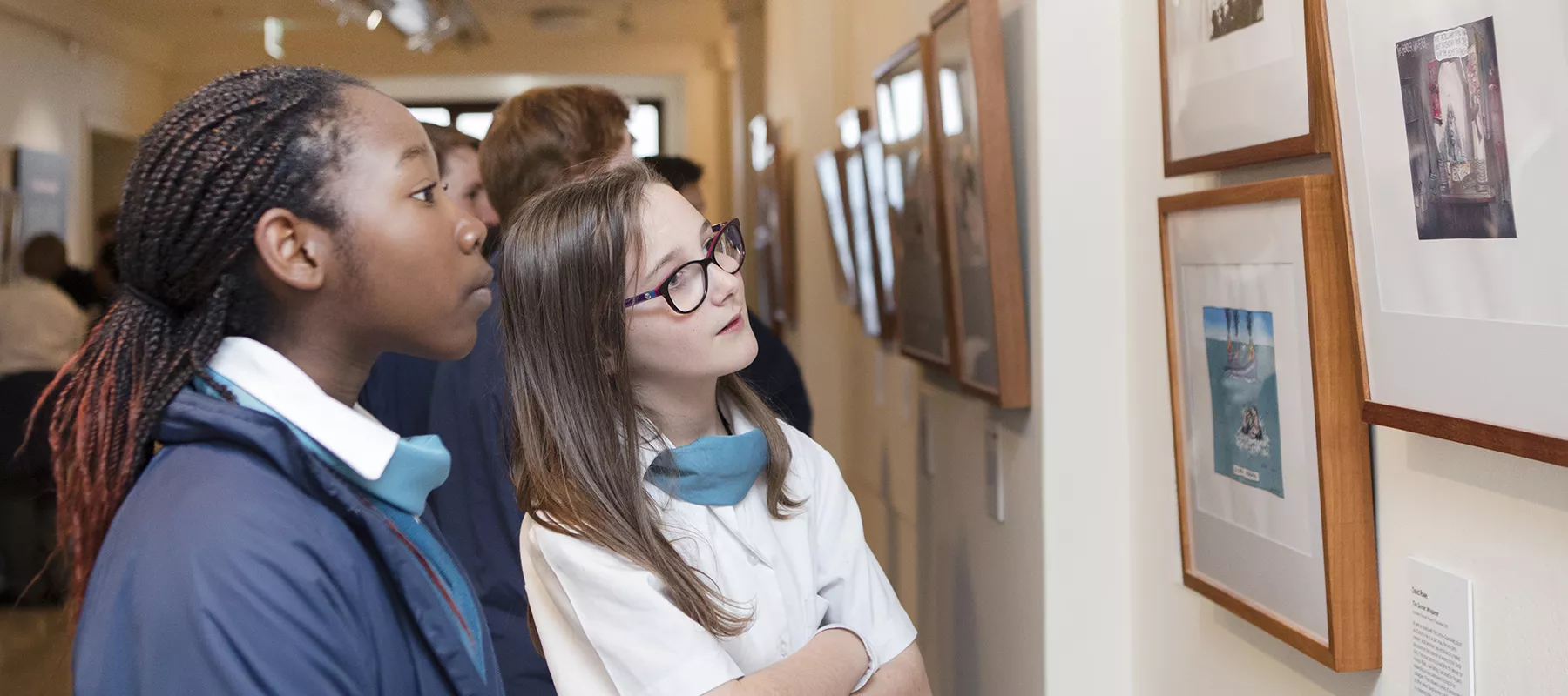 Two school children looking at the artwork in Behind the Lines