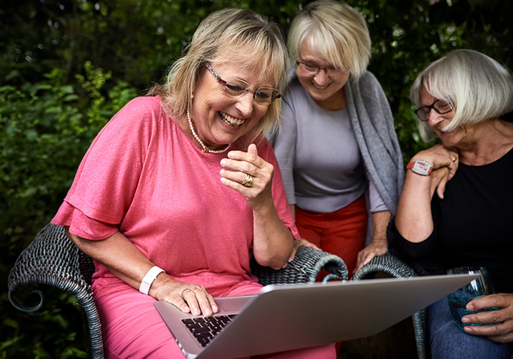 older woman laughing and having fun on a laptop