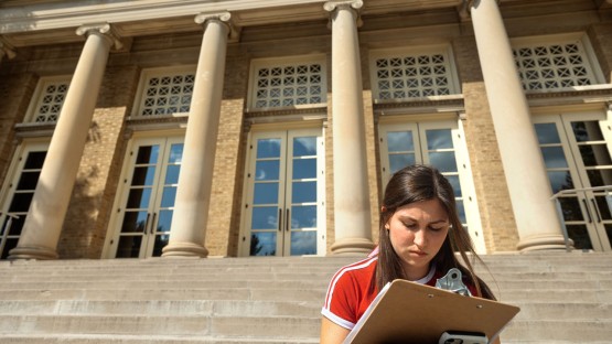 A student does a class assignment near Bailey Hall.