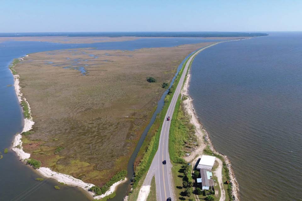 A photograph of a strip of land along the coast, with a long road up the center