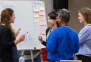 people discussing in front of a whiteboard 