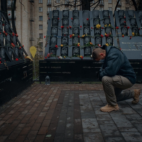 a man kneeling down near tributes to fallen heroes