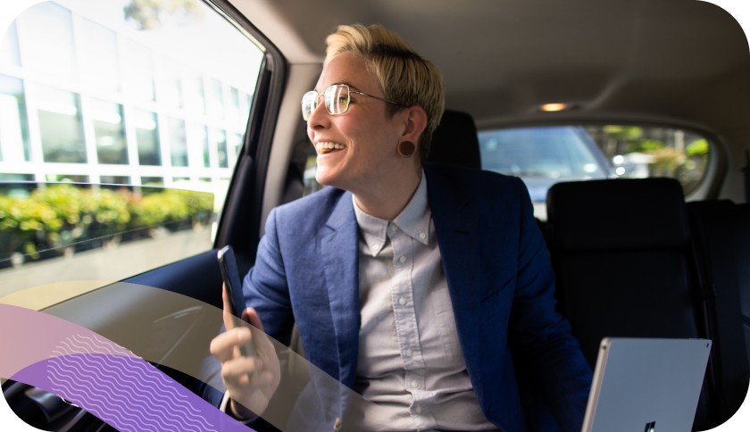 Person holding a laptop while looking out the window of a car