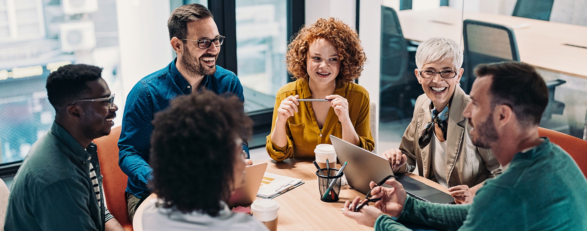 Group of business people having a meeting at a round conference table in a creative office.