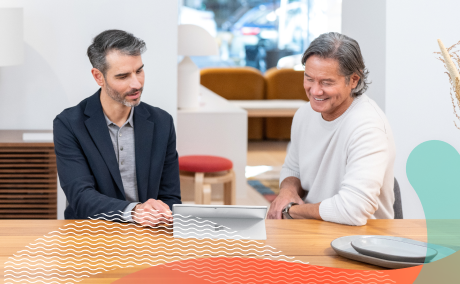 Two people sitting in a work environment with a tablet