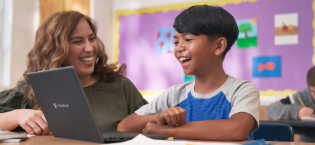 A smiling child and teacher with a laptop