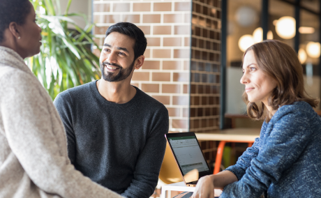 Three people at a table engaged with another person