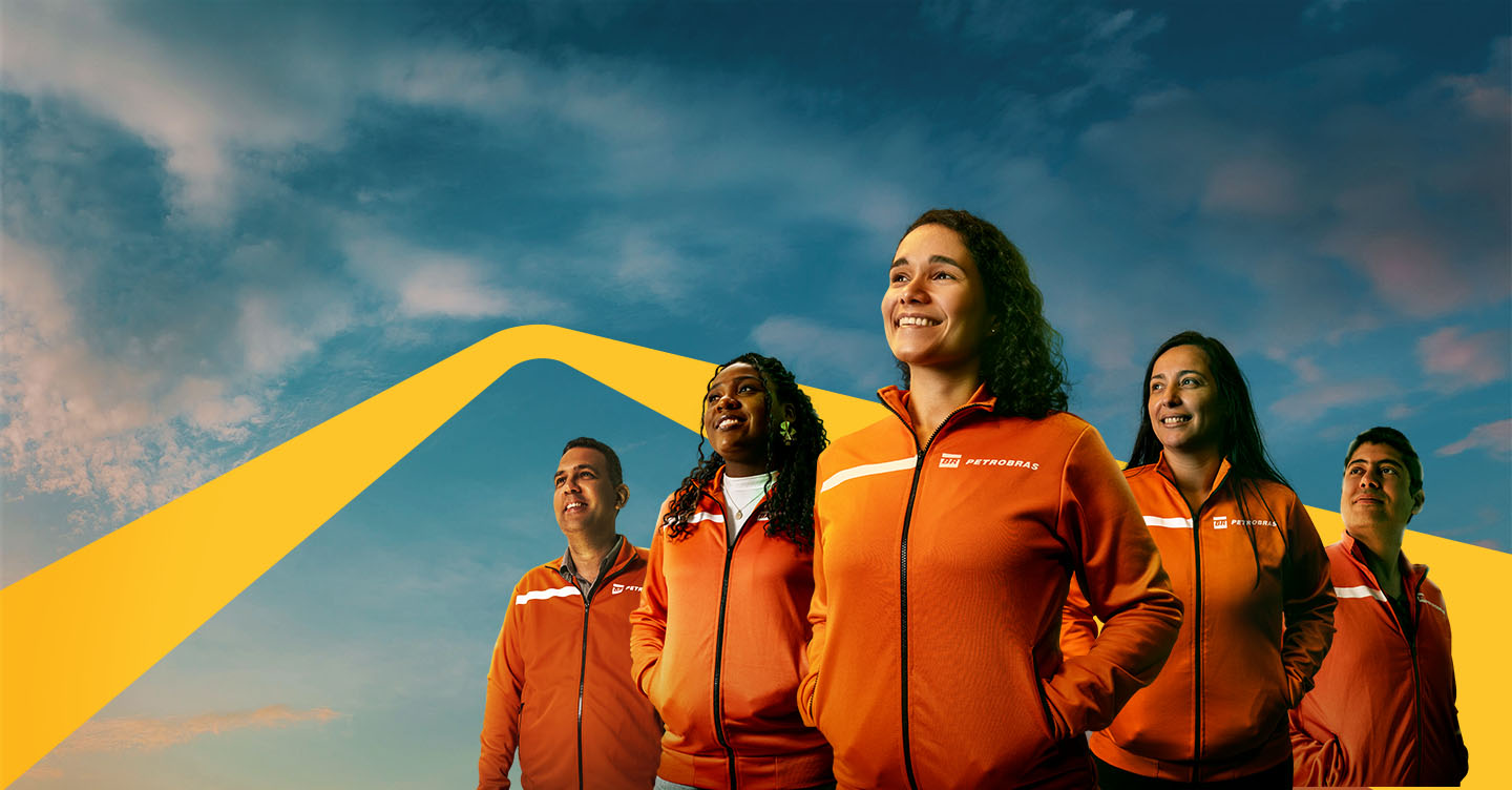 Group of people wearing orange jackets with the Petrobras logo, looking toward the horizon under a blue sky with clouds.