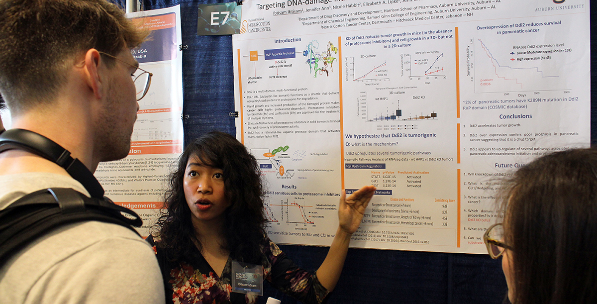 Student stands in front of poster, discussing it