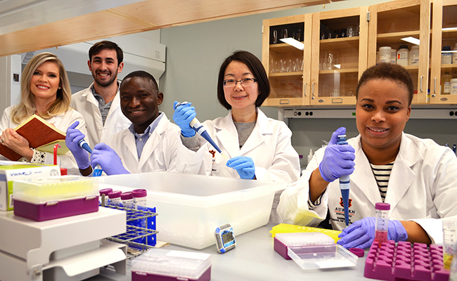 Students and professor stand together in lab