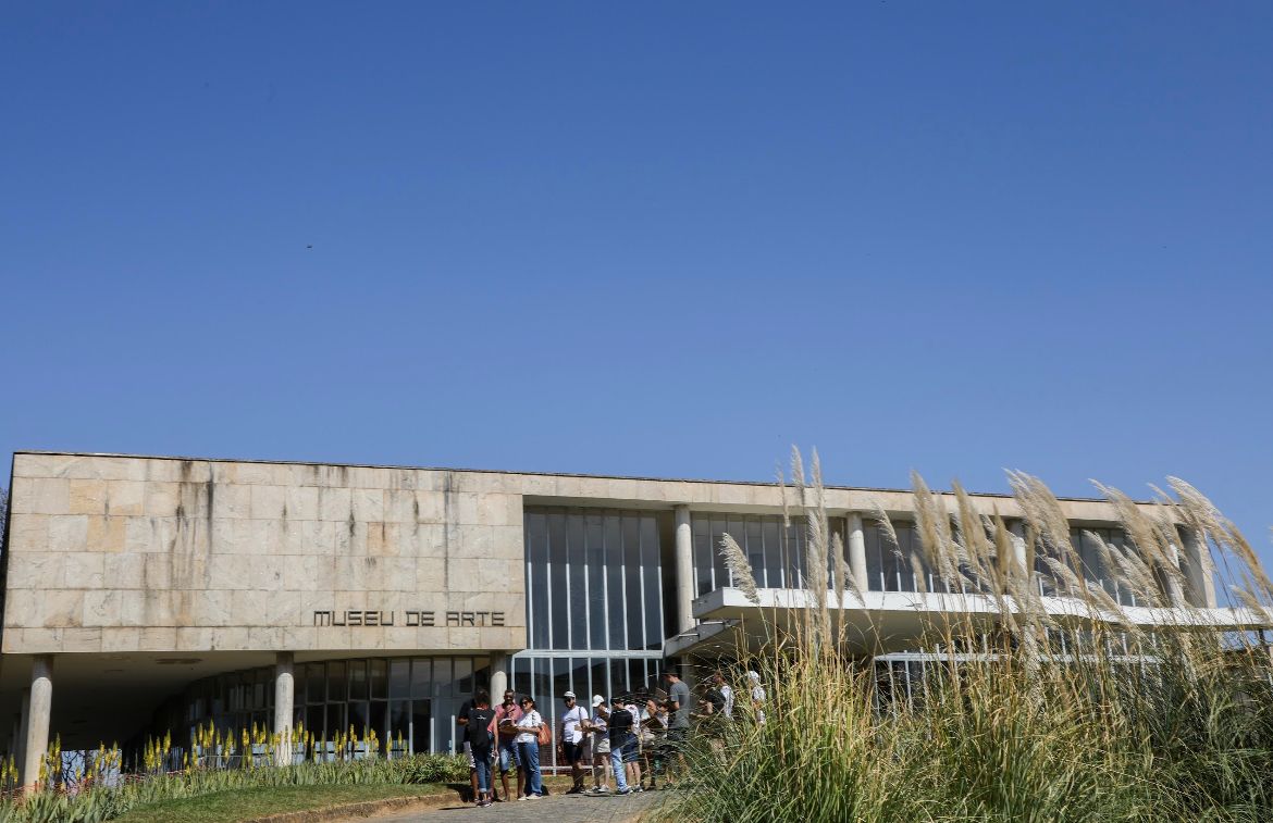 Fachada do Museu de Arte da Pampulha em um dia de sol, céu azul sem nuvens, algumas plantas do jardim na lateral direita