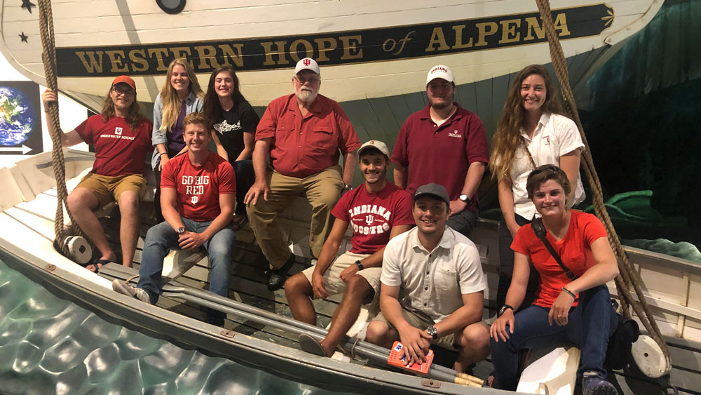 students and teachers pose by a life-size wooden schooner.