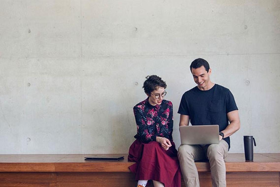 Two students looking at a laptop screen together. 