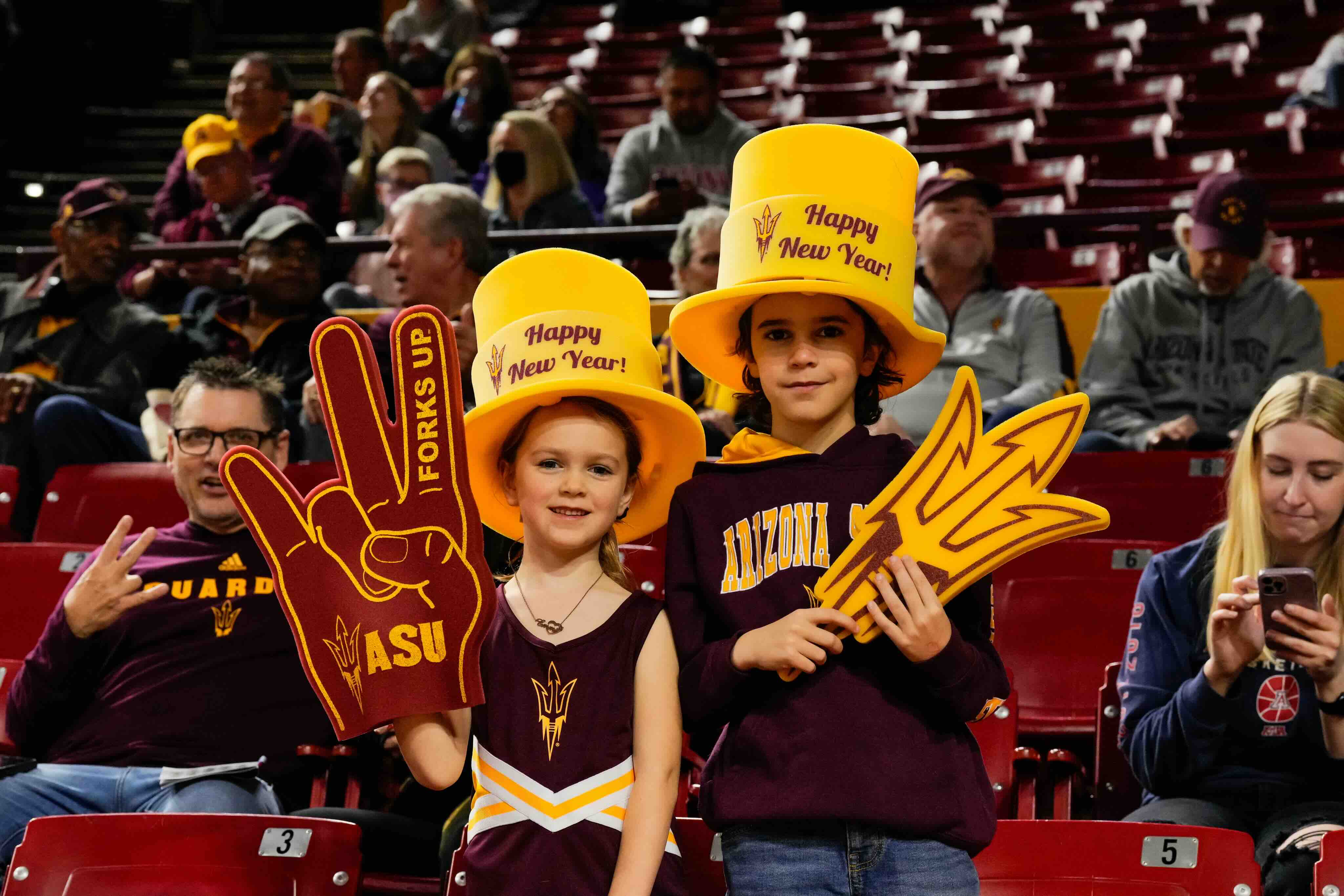 Kids at a Sun Devil game with lots of gear on with foam fingers and hats