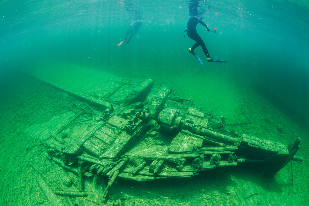 Two divers swim above a shipwreck