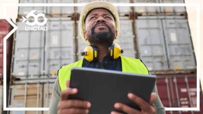 A man uses a digitla device to manage trade in a port