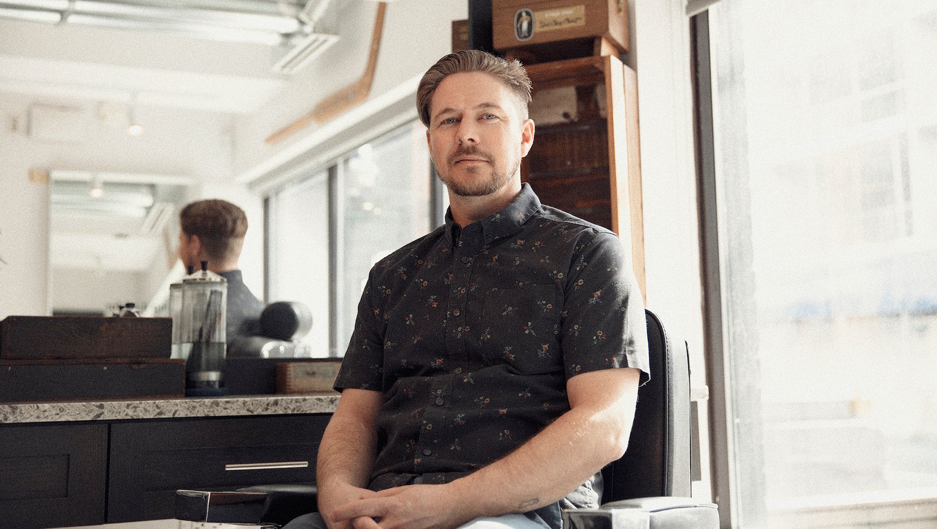 A photograph of Movember supporter Sam Mayer sitting in a barber's chair.