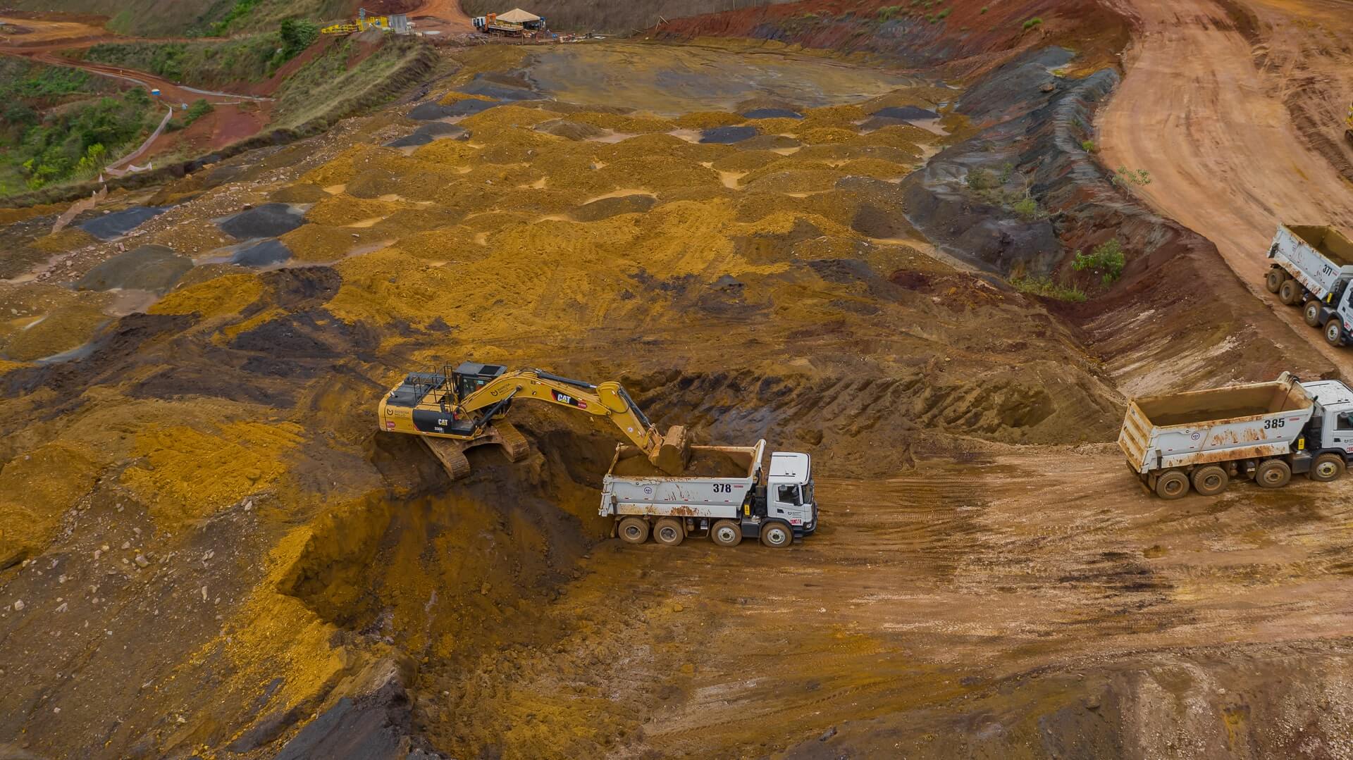 Tractor and truck digging in a sandy area