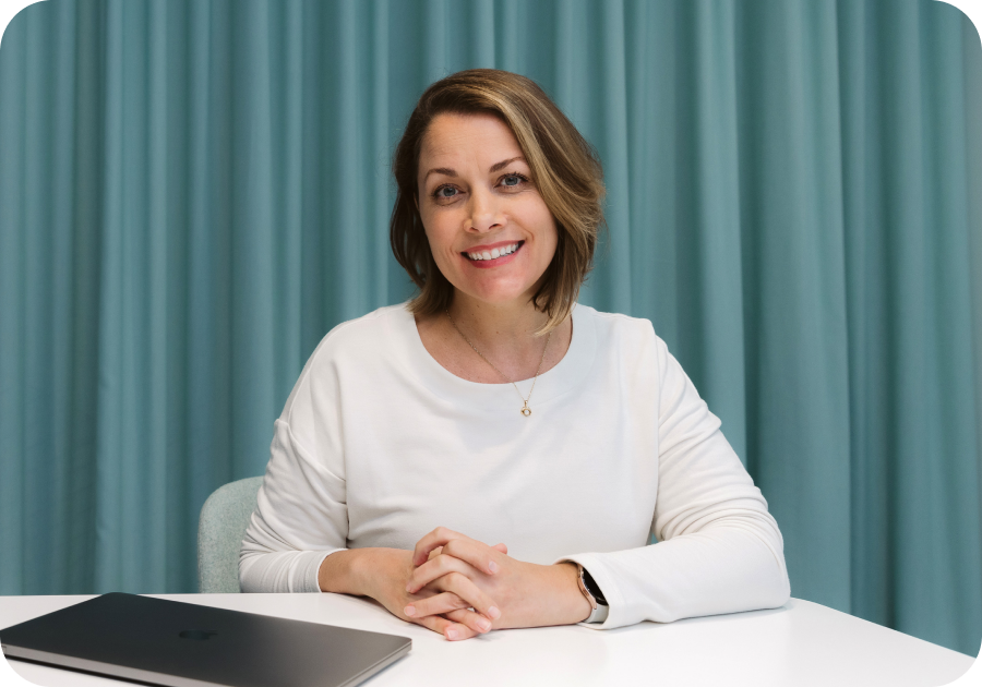 enterprise solutions. woman smiling looking at camera with blue background and laptop on desk in front of her