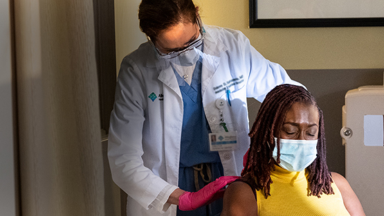 An AHN physician administering nerve block injection to a woman during appointment.