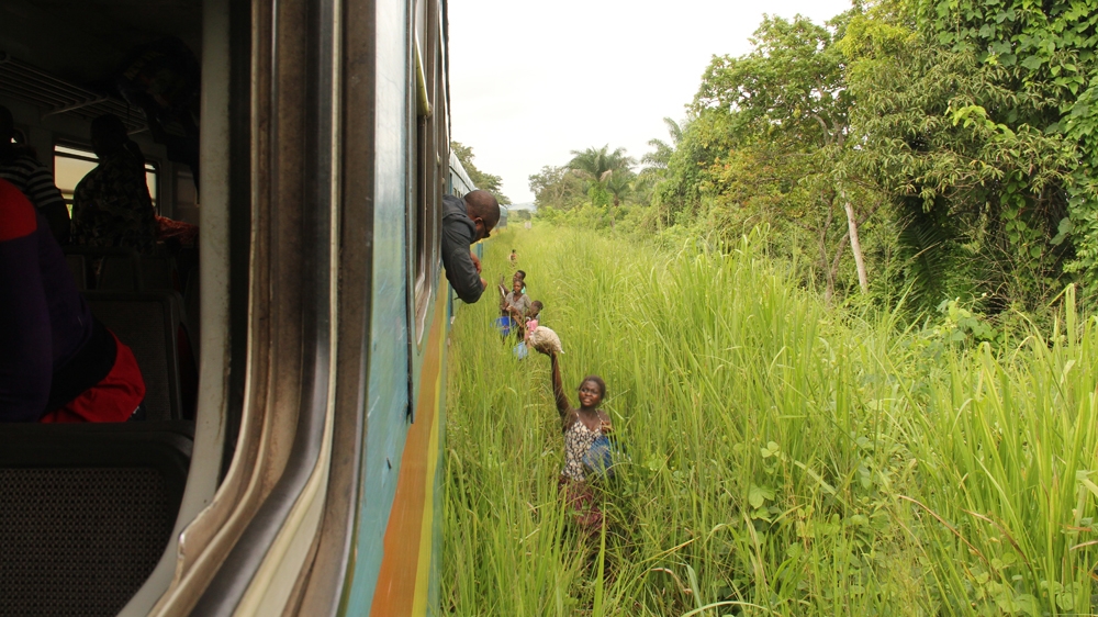 
A passenger buys some food as the train arrives at a station along the route from Matadi to Kinshasa [William Clowes/Al Jazeera]
