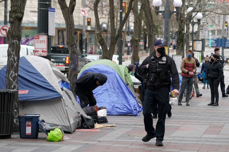 A police officer walks past a homeless encampment