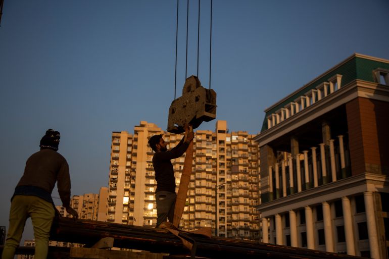 Workers handle building construction material in Greater Noida, India